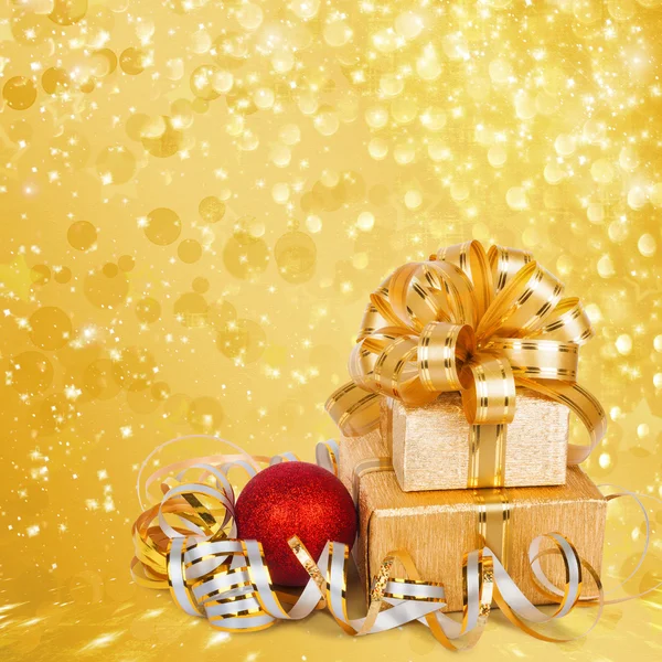 Gift box in gold wrapping paper on a beautiful abstract backgrou — Stock Photo, Image