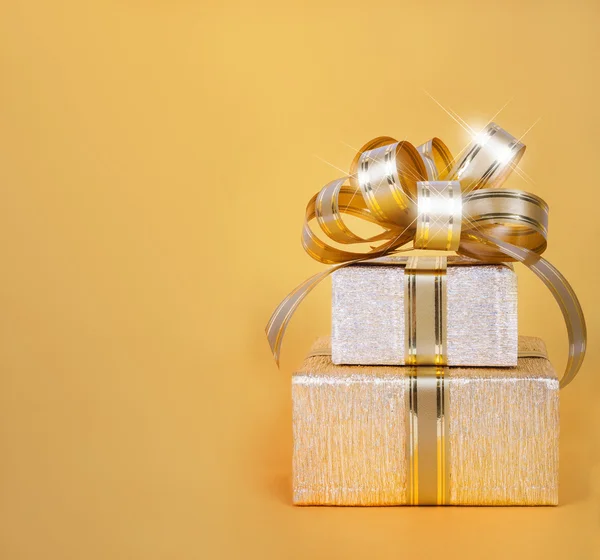 Beautiful Gift box in gold wrapping paper on abstract backgroun — Stock Photo, Image