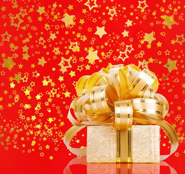 Gift box in gold wrapping paper on a beautiful red abstract back — Stock Photo, Image