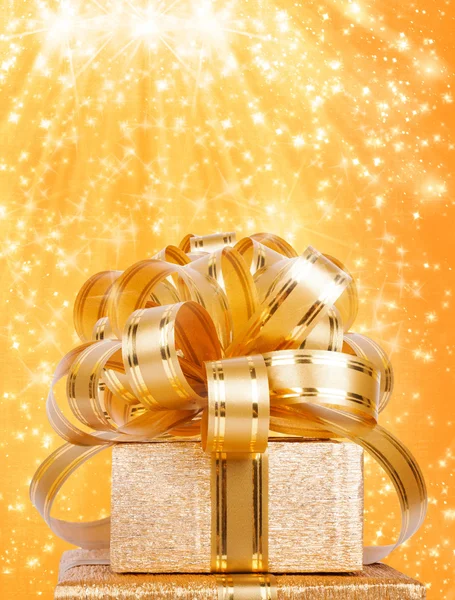 Gift box in gold wrapping paper on a beautiful abstract background — Stock Photo, Image