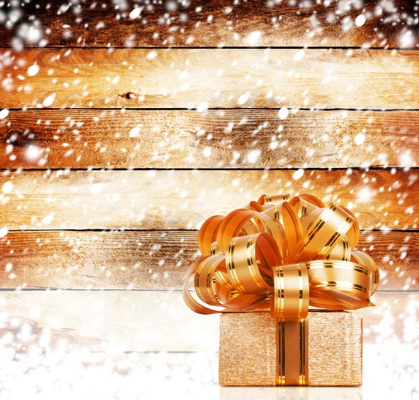 Snow-covered wooden wall with a beautiful gift box and bow — Stock Photo, Image
