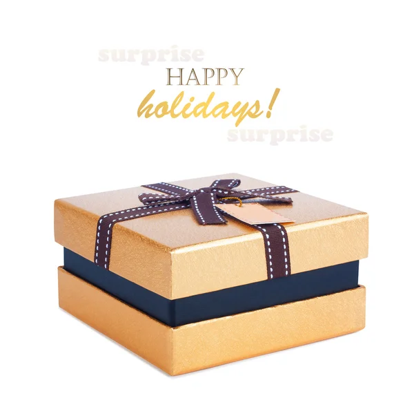 Beautiful gift box in gold paper with bow and label — Stock Photo, Image