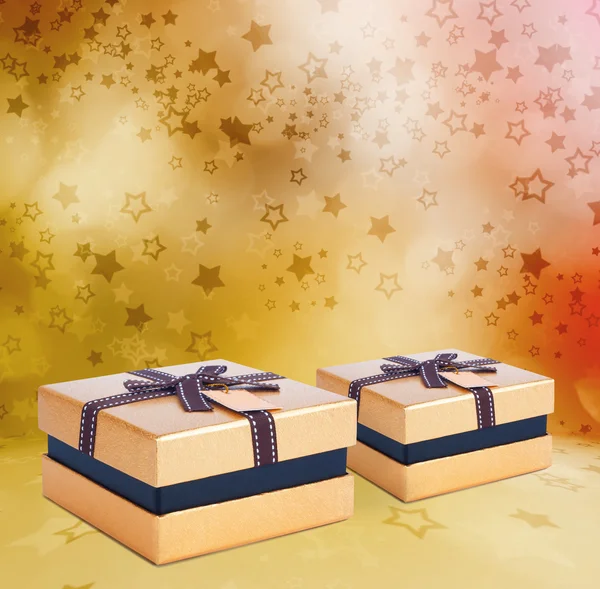 Подарочная золотая коробка с бантом на фоне звезды — стоковое фото