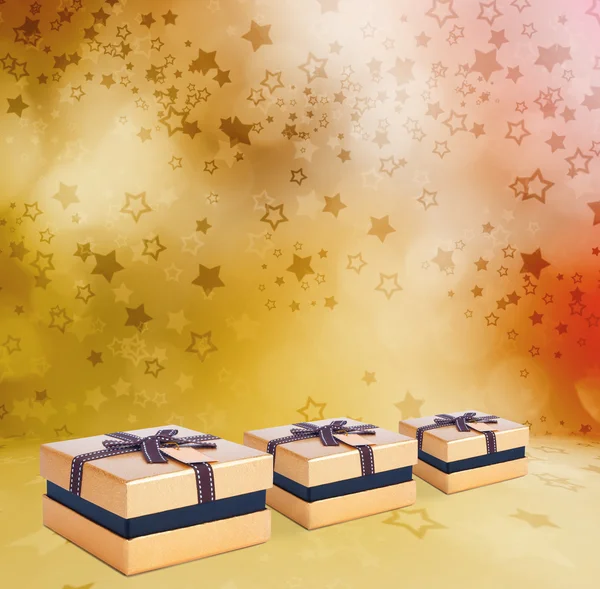 Krásné zlaté krabičky s lukem na pozadí abstraktní hvězda — Stock fotografie
