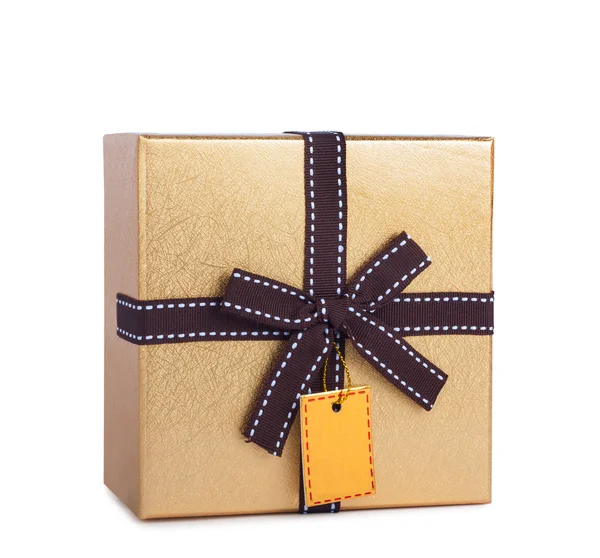 Beautiful gift box in gold paper with bow and label — Stock Photo, Image