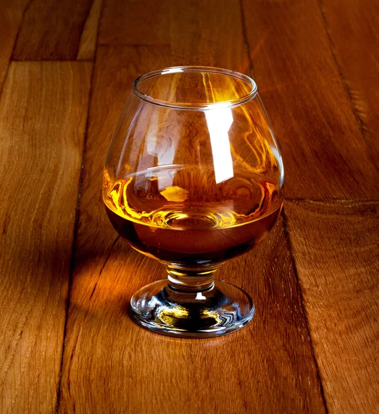 One glass of brandy on antique wooden counter top — Stock Photo, Image