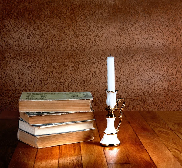 Starý Stoh knih s svícen a hořící svíčka na wo. — Stock fotografie