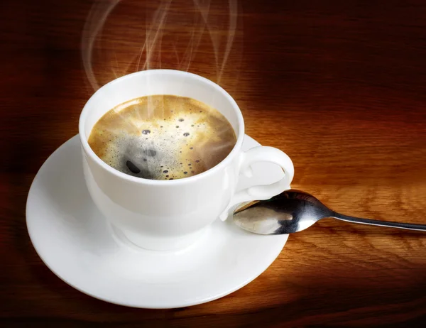Café fresco caliente en una taza blanca con cuchara en la mesa de madera — Foto de Stock