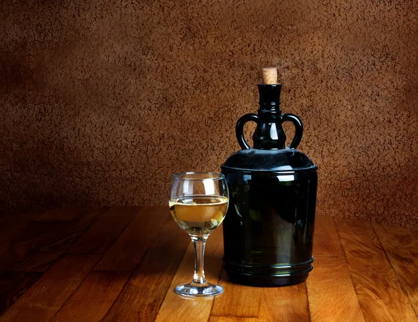 Dusty old bottle and glass of white wine on a wooden table — Stock Photo, Image