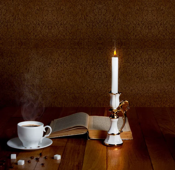 Taza caliente de café fresco en la mesa de madera con vela y libro —  Fotos de Stock