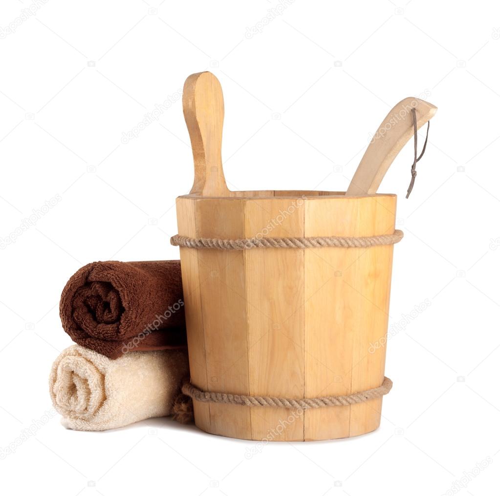 Wooden bucket with ladle for the sauna and stack of clean towels