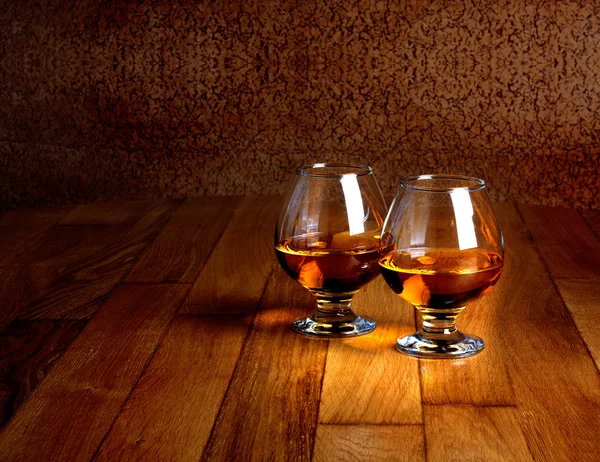 Dos copas de brandy en la encimera de madera vieja —  Fotos de Stock