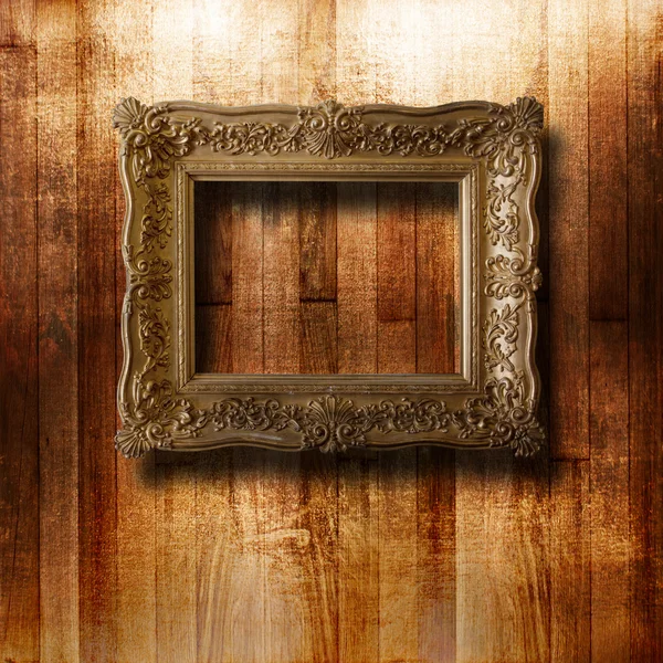 Old gilded picture frame for portrait on the scratched wooden wa — Stock Photo, Image