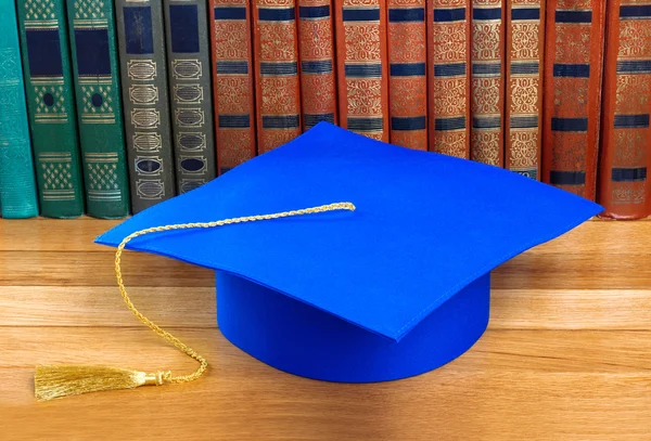 Afstuderen mortarboard boven op de stapel boeken — Stockfoto