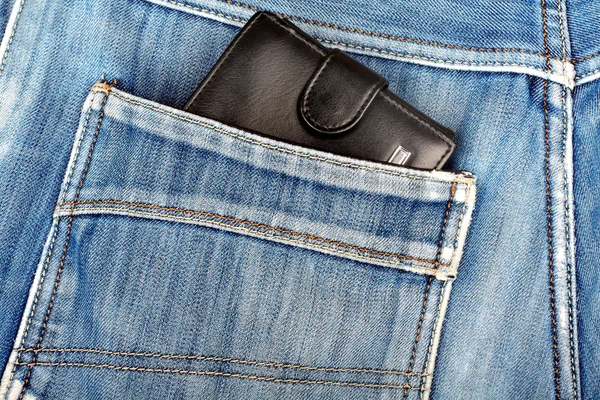 Carteira de couro preto furando no bolso de trás de azul denim — Fotografia de Stock