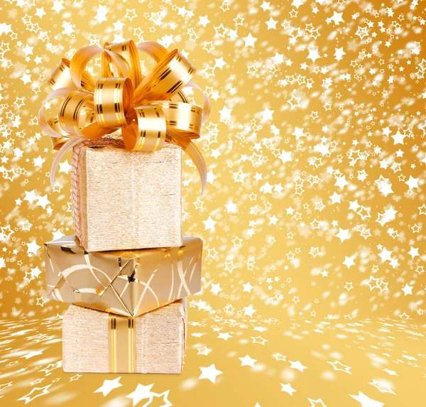 Gift box in gold wrapping paper on a beautiful  abstract backgro — Stock Photo, Image