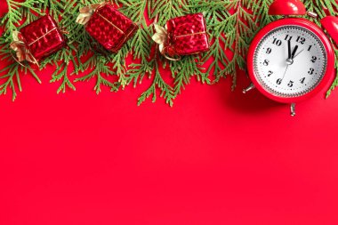 Ağaç dalları ve kağıt zemin üzerinde kırmızı hediye kutuları olan çalar saat. Yılbaşından 5 dakika önce. Yaratıcı tebrik kartı