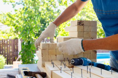 Dolap ustası, matkap, çivi ve çekiçle ahşap mobilyalar yapıyor. Ev yapımı atölyede.