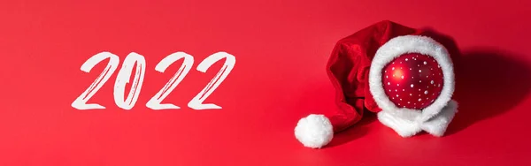 Bunte Weihnachtskugel Mit Weihnachtsmann Hut Auf Rotem Hintergrund Das Symbol — Stockfoto