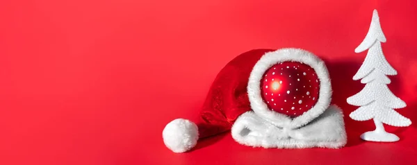 背景に白いトウヒの木があるサンタクラスの帽子の赤いボール 新年とクリスマスのシンボル — ストック写真