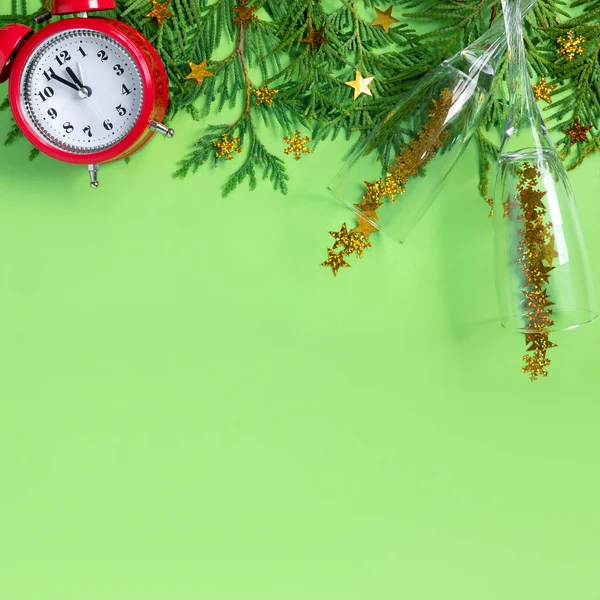 緑の紙の背景にシャンパンの木の枝やガラスと目覚まし時計 新年の5分前 創作グリーティングカード — ストック写真