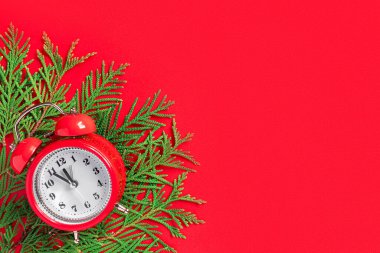 Kırmızı kağıtta ağaç dalları olan çalar saat. Yılbaşından 5 dakika önce. Yaratıcı tebrik kartı