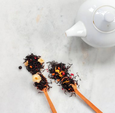 Beyaz çaydanlık ve kaşık dolusu kuru mayalanmış çay otlardan, meyvelerden, meyvelerden ve çiçeklerden mermer tepelerde yapılır..