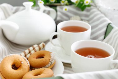 Beyaz ahşap masada lezzetli kurabiyelerle iki fincan sıcak çay..