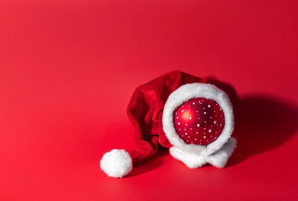 赤い背景のサンタクラスの帽子の多色のクリスマスボール 新年とクリスマスのシンボル — ストック写真