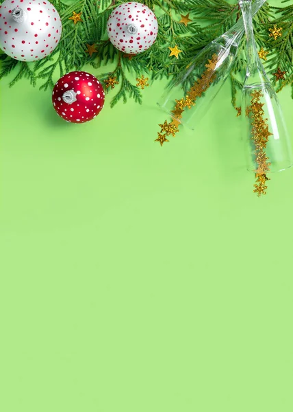 緑の紙の背景にシャンパンの木の枝や眼鏡を持つ多色のクリスマスボール 新年のクリエイティブグリーティングカード — ストック写真