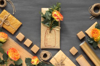 Paket kağıdına sarılmış kırmızı-sarı güller ve boyalı vazo ile hediye. Antika ambalaj kağıtları, dekorasyon için doğal çevre ipinden yapılmış yaylar..