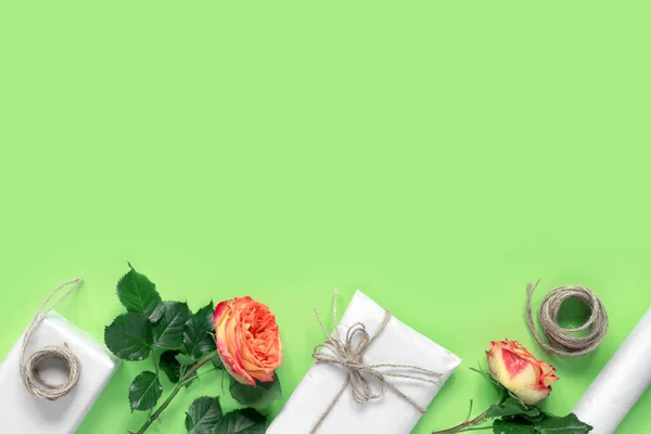 緑の背景でお祝いのための赤い黄色のバラの花束で ロープで結ばれた包装紙のギフトボックス 創作休日プレゼント — ストック写真