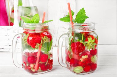 Taze taze meyve suyu, çilek, frenk üzümü ve Bektaşi üzümü beyaz ahşap masada.