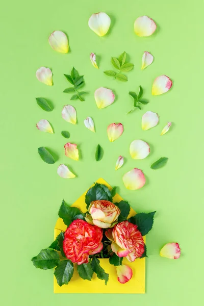 緑の背景に封筒に赤いバラの花束 春休みのミニマルなコンセプト — ストック写真