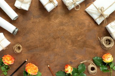 Kağıt ambalajlı hediyeler, klasik sarı paket kağıtları, rulo, ip ve süsleme için kalemler. Altın sarısı arka planda sarı güller..