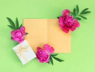 Yeşil arka plan ambalaj kağıdında hediye kutuları olan bir buket güzel pembe şakayık. Bayram tebrik kartı. Metin için kopyalama alanı olan yaratıcı arkaplan.