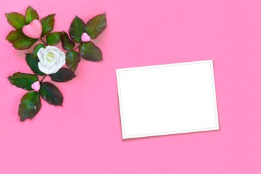 Yeşil yapraklı güzel beyaz güller ve pembe kağıtta Sevgililer Günü için kalp. Yaratıcı tebrik kartı