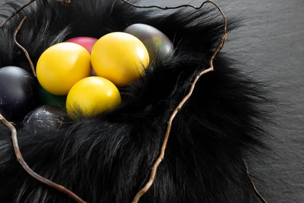 暗い石のテーブルの上に黄色の卵を描いた黒い毛皮の巣 枝を持つお祭りイースターバナー コンセプトデザイン — ストック写真