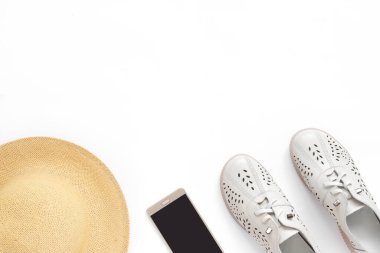 Telefon ve şapkayla izole edilmiş beyaz arka planda tatil kıyafetleri. Düz konum, üst görünüm, kopyalama alanı.