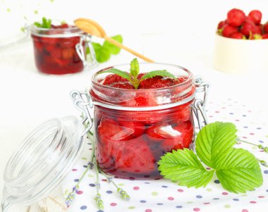 Beyaz ahşap arka planda geleneksel cam kavanozda lezzetli çilek reçeli ve taze böğürtlen.