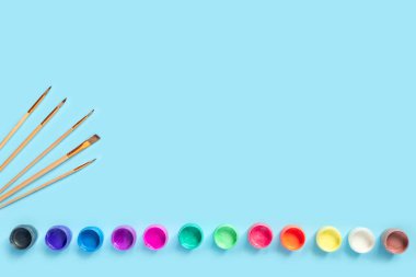 Mavi kağıda resim yapmak için boya ve fırçalar.