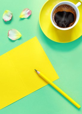 Bir buket güzel sarı gül ve yeşil kağıttan arka planda bir fincan taze taze aromalı kahve. Metnin için defter kağıdı ve kalem