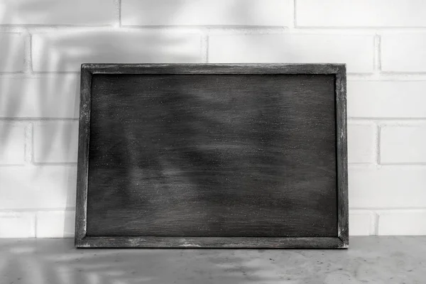 Mockup art of vintage chalkboard background texture with old vintage wooden frame with leaf shadow, image for work about design element concept.