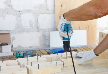 Dolap ustası, matkap, çivi ve çekiçle ahşap mobilyalar yapıyor. Ev yapımı atölyede.