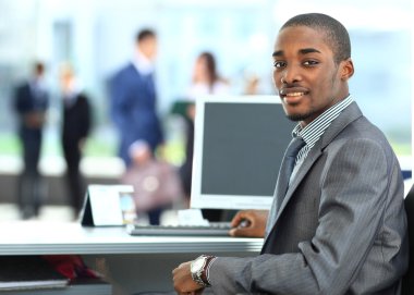 Portrait of a happy African American entrepreneur displaying computer laptop in office clipart