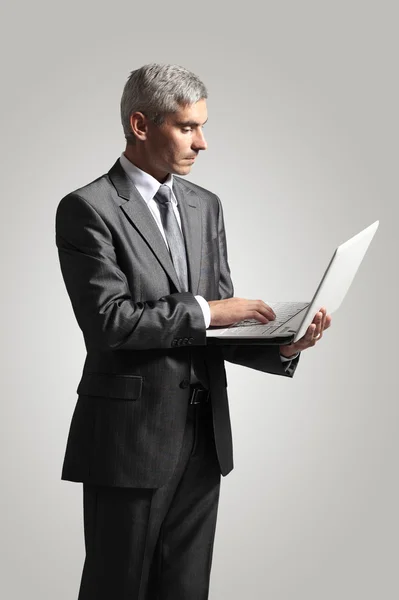 Bonito empresário sorridente trabalhando com laptop. Isolado sobre fundo branco — Fotografia de Stock