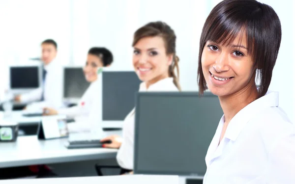 Mulher de negócios com um computador no escritório com um grupo atrás — Fotografia de Stock