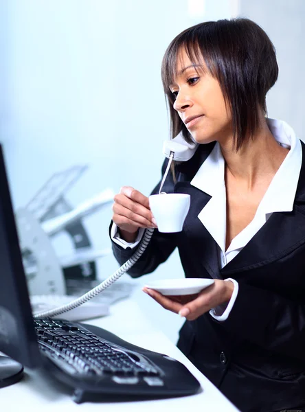 Бізнес-леді, сидячи за столом в офісному лобі, п'є каву . — стокове фото