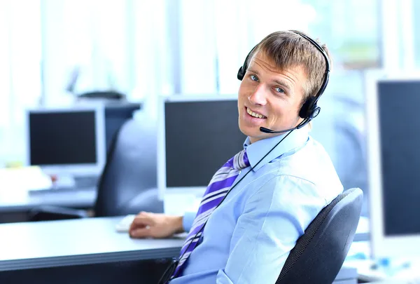 Joven feliz trabajando en el centro de llamadas, usando headse — Foto de Stock