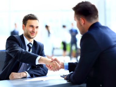 Toplantı sırasında iki iş arkadaşı el sıkışıyor.